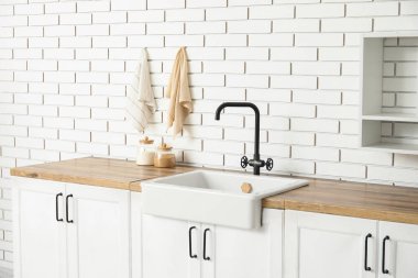 Beyaz tezgahlı, lavabolu ve raflı şık bir mutfak.