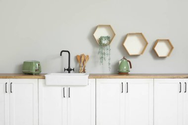 Beyaz tezgahları, aletleri ve lavabosu olan şık bir mutfak.