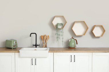 Beyaz tezgahları, aletleri ve lavabosu olan şık bir mutfak.