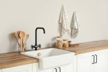 Beyaz tezgahlı, çatallı ve lavabolu şık bir mutfak.