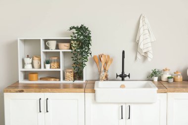 Beyaz tezgahlı, raflı, çatal bıçaklı ve lavabolu şık bir mutfak.