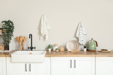 Beyaz tezgahlı, raflı, çatal bıçaklı ve lavabolu şık bir mutfak.