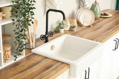 Beyaz tezgahlı, raflı, çatal bıçaklı ve lavabolu şık bir mutfak.