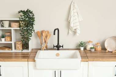 Beyaz tezgahlı, raflı, çatal bıçaklı ve lavabolu şık bir mutfak.