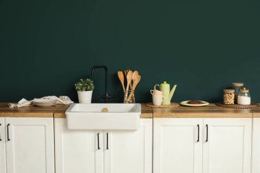 Beyaz tezgahlı, çatallı ve lavabolu şık bir mutfak.