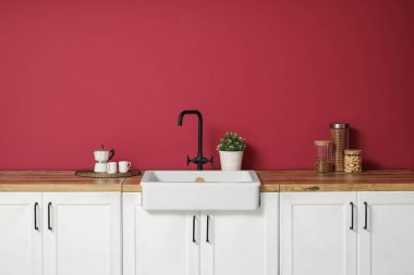 Beyaz tezgahlar ev bitkisi, kavanozlar ise modern mutfağın içindeki kırmızı duvarın yakınındaki ürünler.