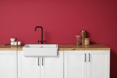 Kahve makineli beyaz tezgahlar, fincanlar ve modern mutfağın içinde ürünleri olan kavanozlar, yakın plan.