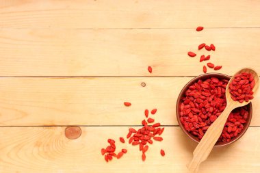 Ahşap arka planda kase, kaşık ve kurutulmuş kurt üzümü kompozisyonu