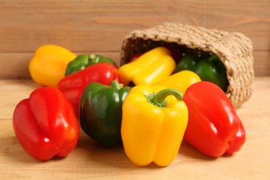 Tahta arka planda taze dolma biberli hasır sepet.