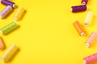 Sarı arkaplanda renkli iplik makaralarından yapılmış çerçeve