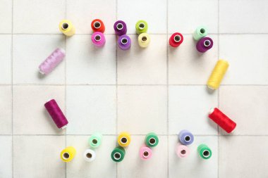 Beyaz fayans arkaplanındaki renkli iplik havuzlarından yapılmış çerçeve