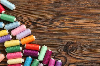 Ahşap arka plan üzerinde renkli iplik makaralar
