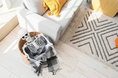 Cadılar Bayramı için dekore edilmiş insan iskeleti ve ekoseli sepet.