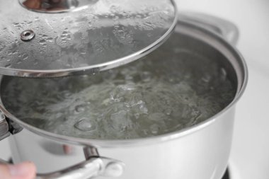 Mutfakta kaynar su bulunan paslanmaz çelik tencere, yakın plan.