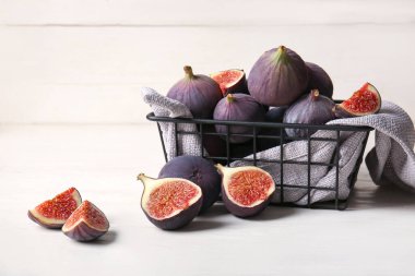 Beyaz ahşap arka planda taze incir dolu sepet.