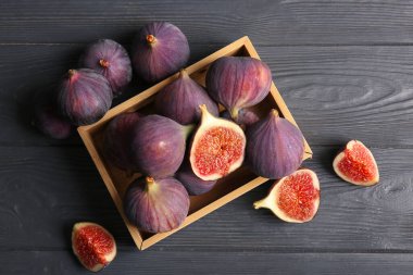 Siyah ahşap arka planda taze incir dolu bir kutu.