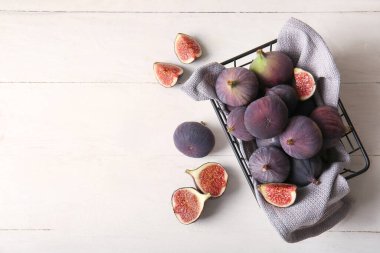 Beyaz ahşap arka planda taze incir dolu sepet.