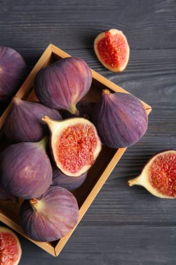 Siyah ahşap arka planda taze incir dolu bir kutu.