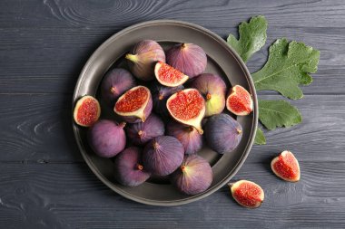 Siyah ahşap arka planda taze taze incir tabağı.