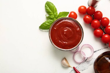 Bir kase lezzetli domates sosu ve beyaz arka planda farklı malzemeler.