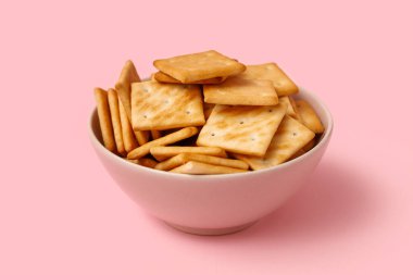 Pembe arka planda lezzetli krakerler olan kase, yakın plan.