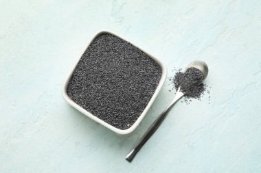 Açık mavi arka planda haşhaş tohumlu kase ve kaşık