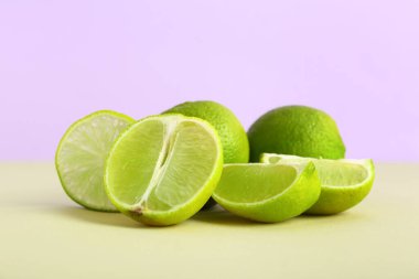 Yeşil masada taze limonlar, leylak arkaplanına karşı