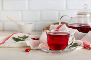 Beyaz masada bir bardak sıcak gül çayı.