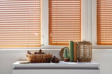 Pencerenin yanındaki masada külahlı, kitaplı ve fenerli sepet.