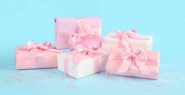 Güzel fiyonklu hediye kutuları ve mavi arka planda konfeti.