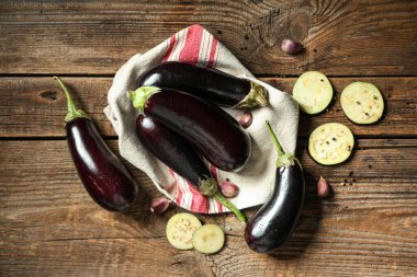 Dilimlenmiş taze patlıcan, karabiber ve ahşap arka planda sarımsak.