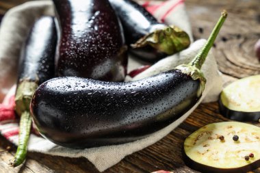 Dilimlenmiş taze patlıcanlar ve ahşap arka planda biber.