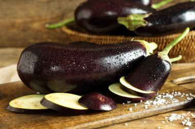 Dilimlenmiş taze patlıcanlar ve ahşap arka planda deniz tuzu.