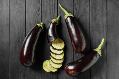 Koyu ahşap arka planda dilimleri olan taze patlıcanlar.