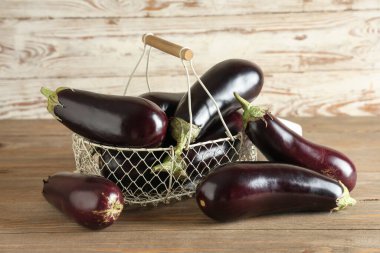 Tahta arka planda taze patlıcan dolu sepet.