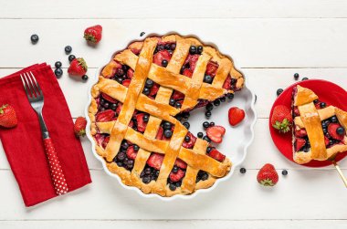 Beyaz ahşap arka planda lezzetli meyveli turta ve çatallı fırın yemeği.