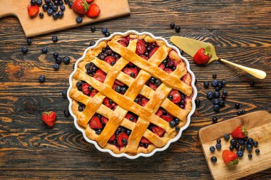 Ahşap arka planda lezzetli meyveli turta ve spatula ile pişirme yemeği.