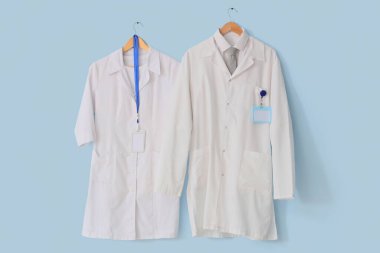 Mavi arka planda asılı beyaz sağlık üniformaları.