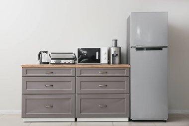 Farklı modern ev aletleri tezgahta beyaz duvarda buzdolabı var.