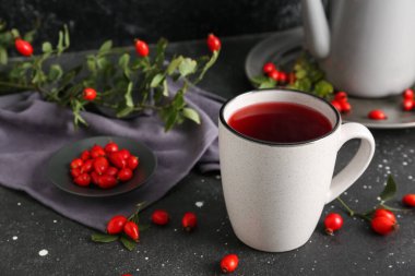 Bir fincan sıcak gül çayı ve siyah arka planda böğürtlen, yakın plan.