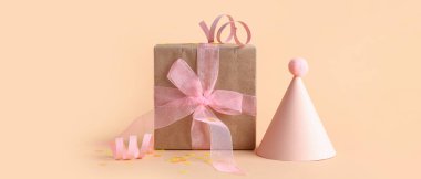 Parti şapkası hediye paketi ve turuncu arka planda konfeti.