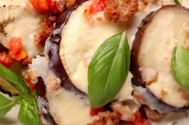 Fırında patlıcan dilimleri, et, sebze, peynir ve fesleğen yaprakları, yakın plan.