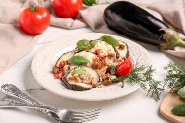 Fırında patlıcan dilimleri, domatesler, dereotu ve fesleğen yapraklı mermer zemin