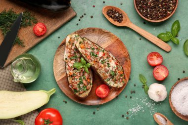 Doldurulmuş patlıcan, domates, biber, fesleğen yaprağı ve yeşil grunge arka planda sarımsaklı bir tabak.