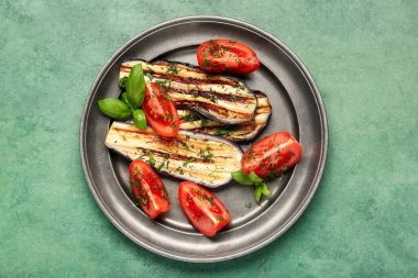 Lezzetli ızgara patlıcan, dereotu, domates ve fesleğen yapraklı yeşil grunge arka planda.