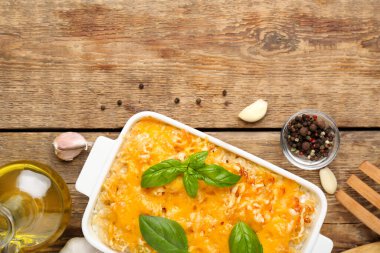 Ahşap arka planda fesleğen yapraklı ve peynirli makarna pişirmek.