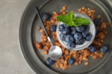 Bir bardak lezzetli chia tohumu pudingi granola ve gri arkaplanda yaban mersini.