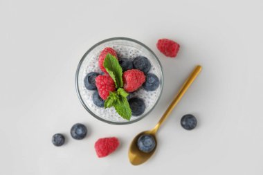 Beyaz arka planda yaban mersini, ahududu ve nane yapraklı lezzetli chia tohumu pudingi.