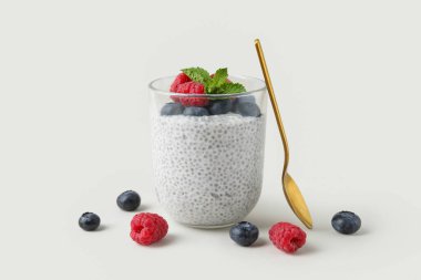 Beyaz arka planda yaban mersini, ahududu ve nane yapraklı lezzetli chia tohumu pudingi.