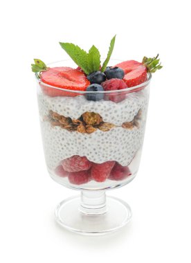 Bir bardak nane yapraklı chia tohumu pudingi, granola ve böğürtlen beyaz arka planda.